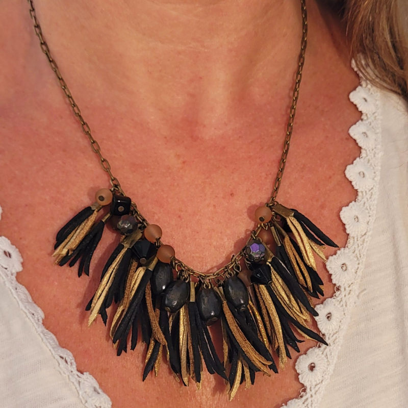 Collier chaîne bronze vieilli et assortiment de perles noire beige et pompon de suédine noir beige et doré pailleté